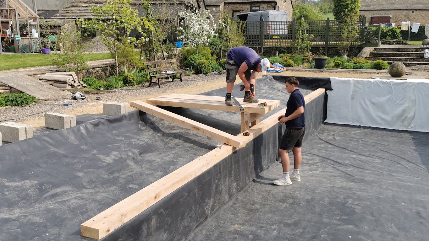 Construction team converting traditional pool into natural pond”
